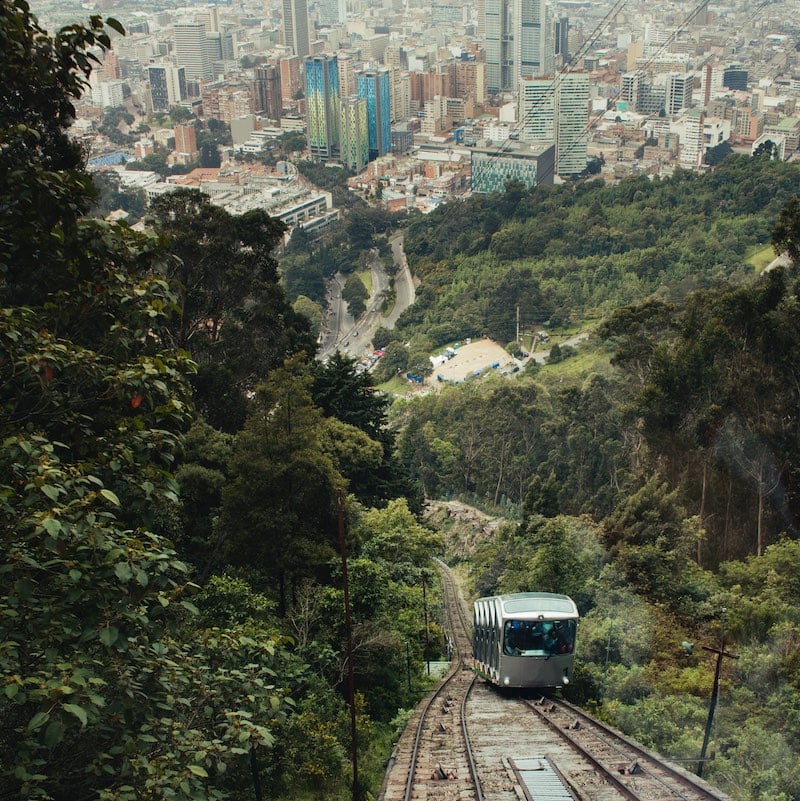 A funicular arrives at the teleferico system of monserrate in Bogota, which was opened in 1955, many buildings and trees can be seen behind, this dramatic shot shows the relationship between the mountain and the city.