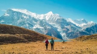Couple Of Backpackers In A Desolate Location In Nepal, South Asia With Snowy Mountains In The Background