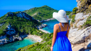 Girl with sun hat at Porto Timoni beach at Afionas is a paradise double beach with crystal clear azure water in Corfu
