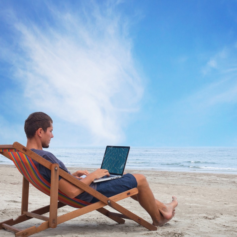 Male Digital Nomad Working On A Beach Location