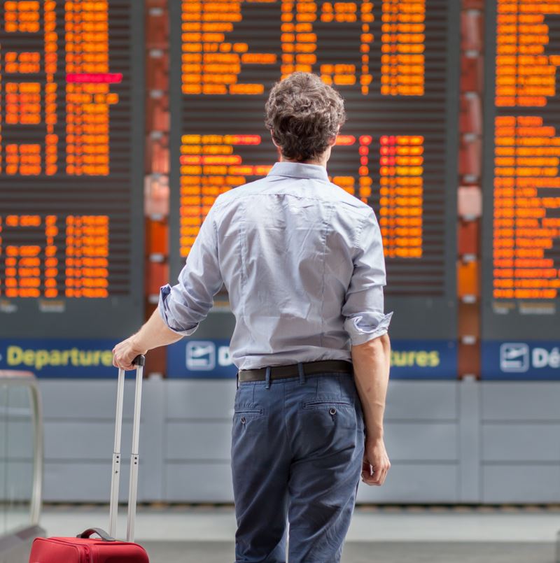 Man staring at a flight information board in an airport canceled flight delayed flight