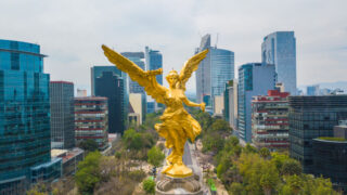 Frontal aerial view of the statue of the angel of independence on Reforma Avenue with Chapultepec forest.