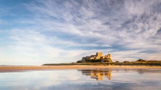 A photo of Bamburgh castle reflected in the still water below