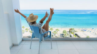 A woman sitting in an apartment overlooking a beautiful beach view