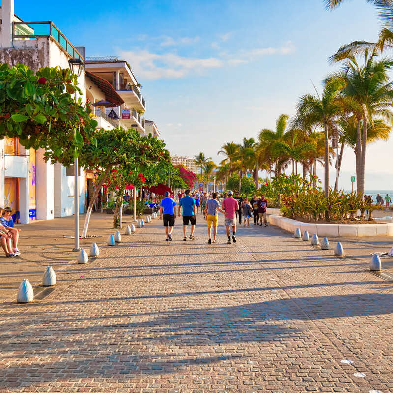 Tourists Walking Along The Malecon, A Beachfront Path In Puerto Vallarta, On The Pacific Coast Of Mexico