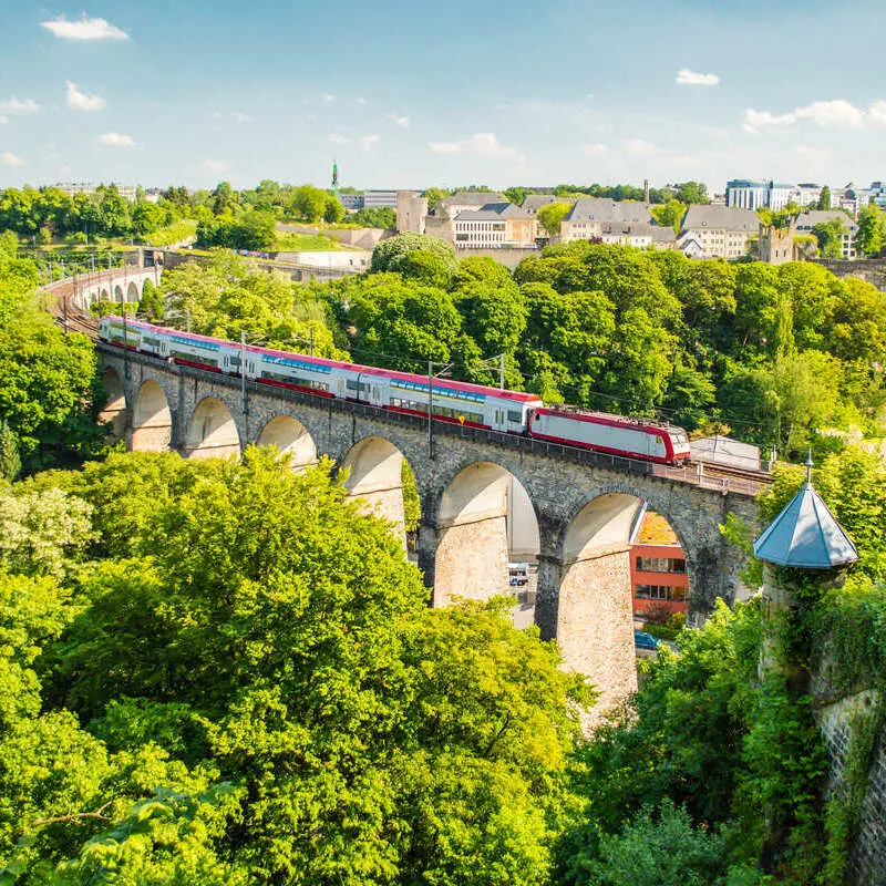 A Luxembourg Train Crossing A Bridge Spanning Luxembourg City, Western Europe