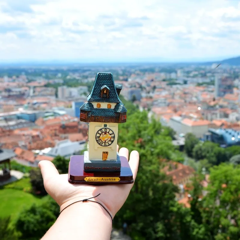 A Young Man Holding A Miniature Clock Tower Atop The Fortress In Graz, The Second Largest City In Austria, Central Europe