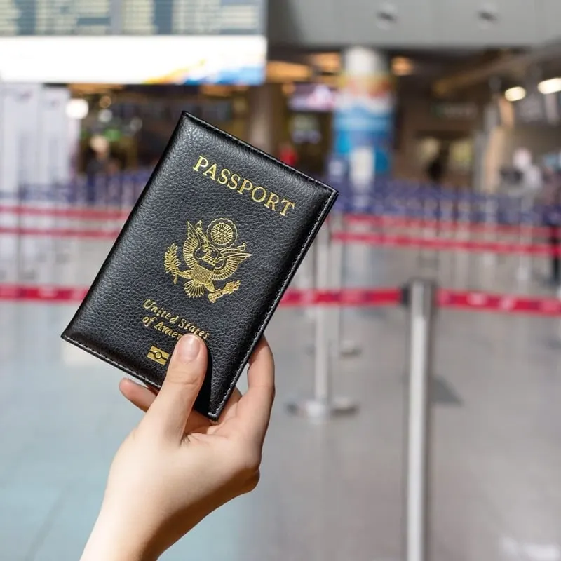 An American Traveler Holding Up A US American Passport Case As They Wait To Board An International Flight At The Airport
