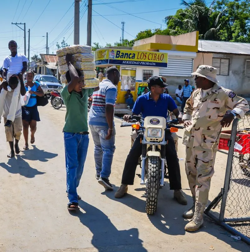 CESFRONT patrol officer talking to haitians at the border of haiti and the dominican republic