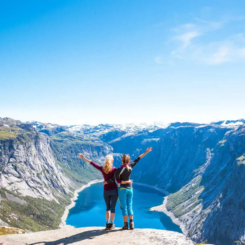Couple Of Young Female Tourists Overlooking A Fjord In Norway, Scandinavia, Northern Europe