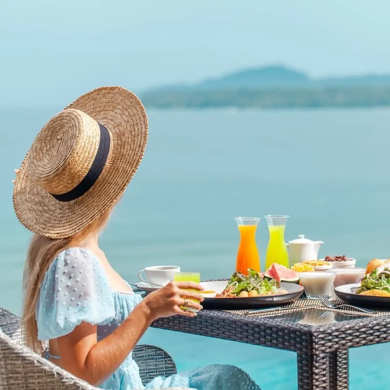 Female Tourist Enjoying Breakfast Alfresco At A Beachfront Hotel Or Resort In An Unspecified Coastal Location