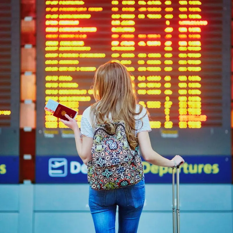 Woman standing in front of flight departures board