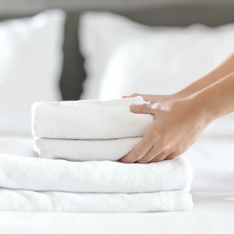 Hands placing fresh towels on bed