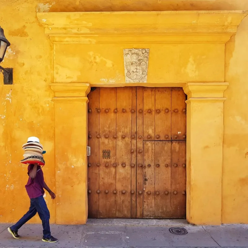 hat vendor walking by traditional colombia building