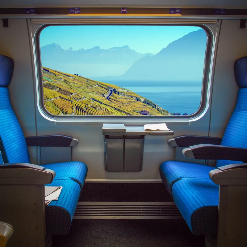 the mountains and waters of Switzerland are vibrantly framed from inside a passenger train