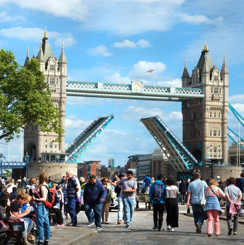 People walking along the river in London with Tower bridge in background