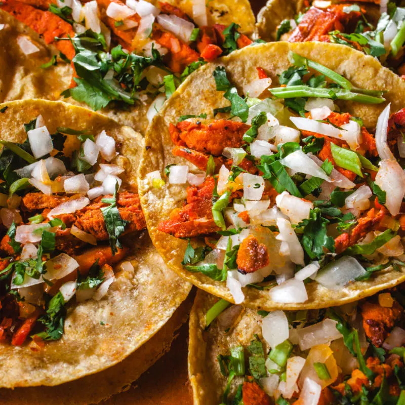 Mexican food, tacos al pastor with onions, peppers and other toppings. 