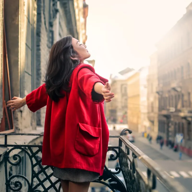 Solo female traveler in a red coat on balcony in Budapest, Hungary, Europe