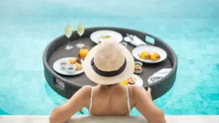 A woman eating a luxury breakfast in a pool