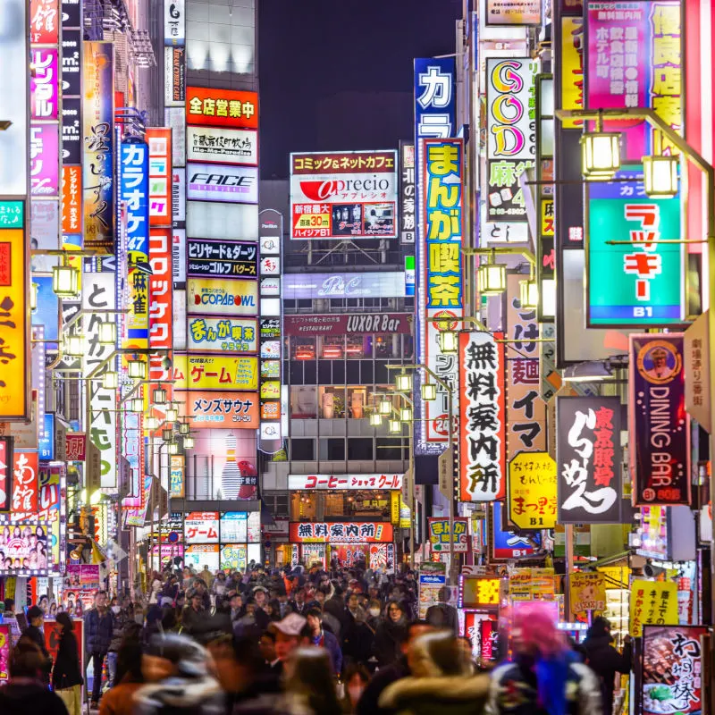 A busy street in Tokyo is lit up by many bright signs