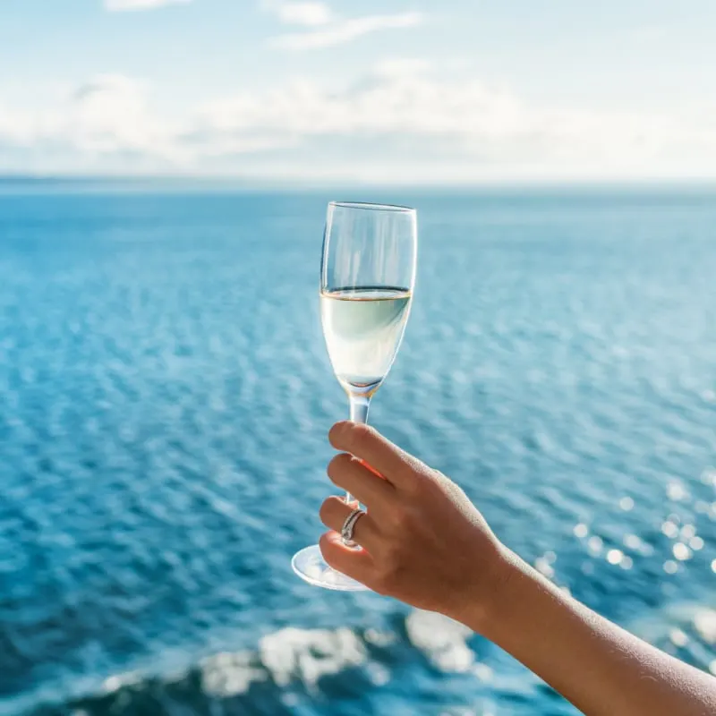 woman holds champagne on a cruise ship with engagement ring - honeymoon, girl's trip, vacaiton