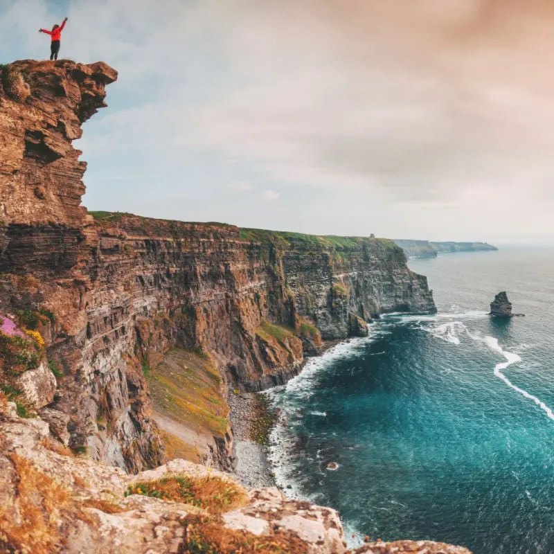 Woman or solo female traveler at the cliffs of Moher in Ireland