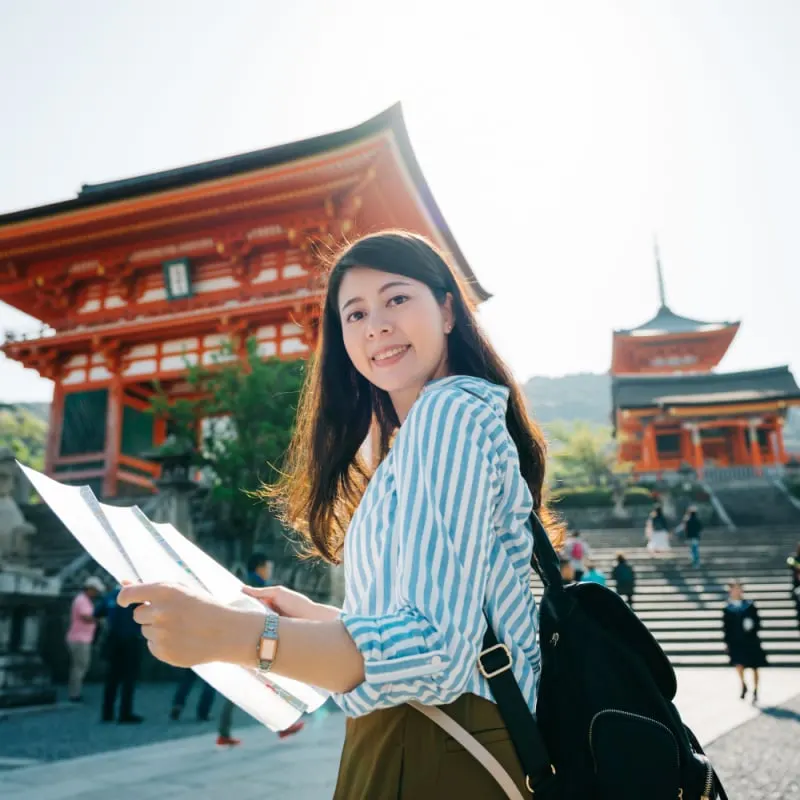 Woman with map standing outside Japanese temple as solo female traveler