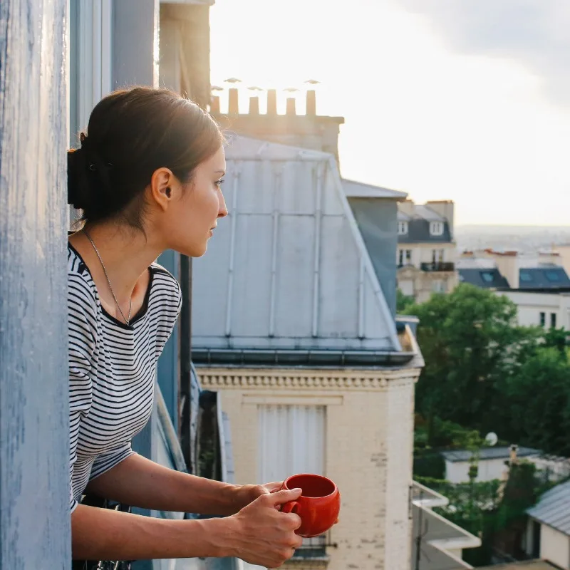 Young Woman Enjoying The View From An Apartment In Paris, France